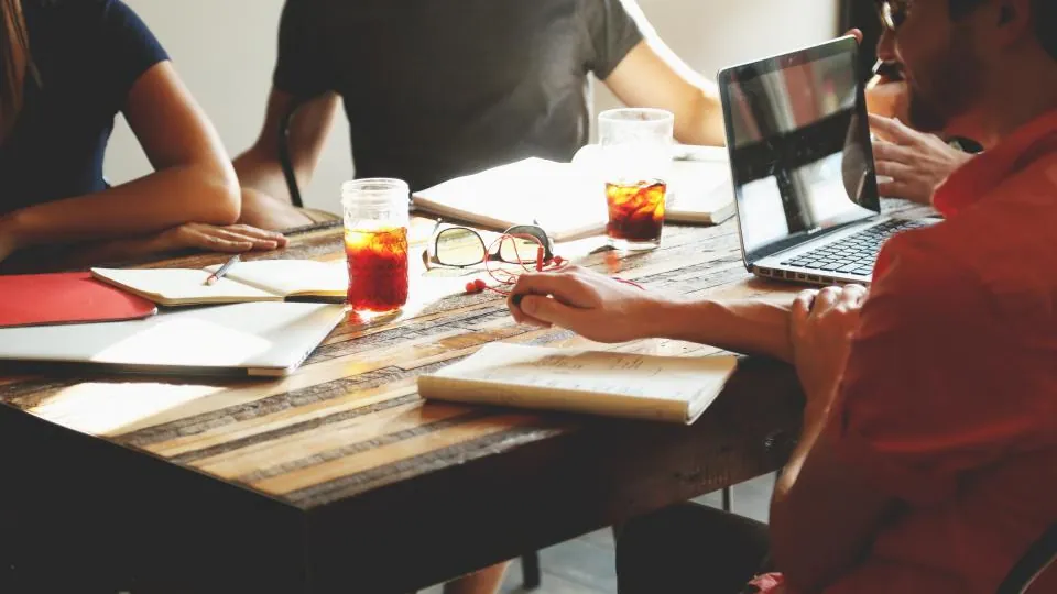 Small team discussing plans around a table with a laptop