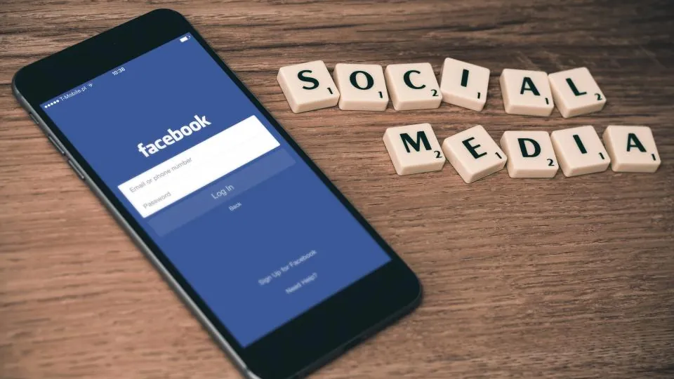 Smartphone showing the Facebook login screen next to tiles spelling social media