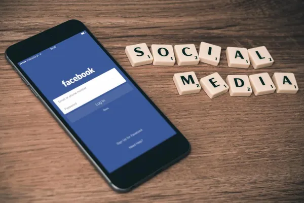 Smartphone showing the Facebook login screen next to tiles spelling social media