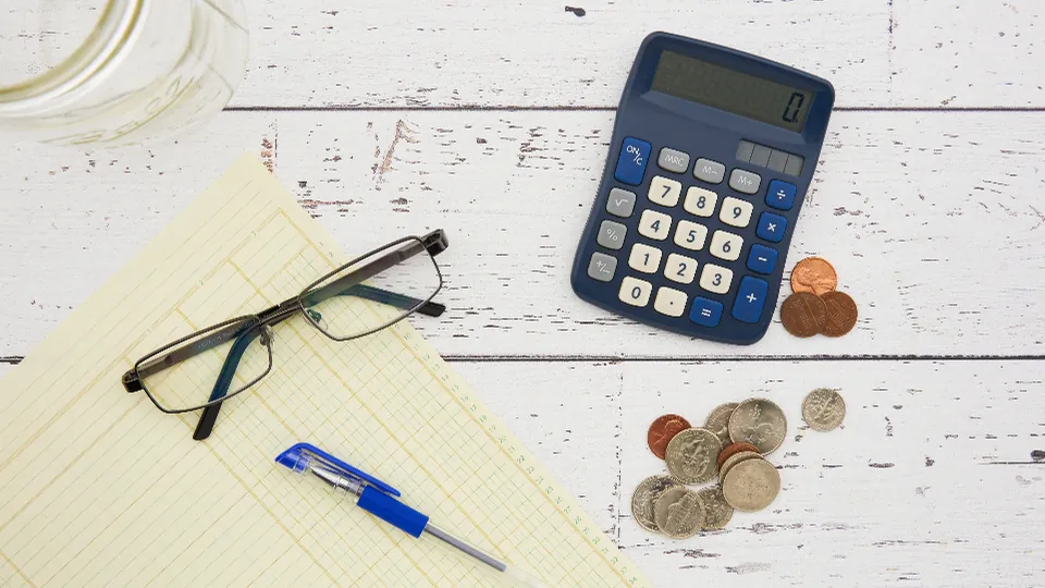 Calculator, coins and glasses on a desk