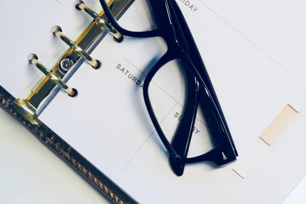 Diary open on a desk with a pair of glasses