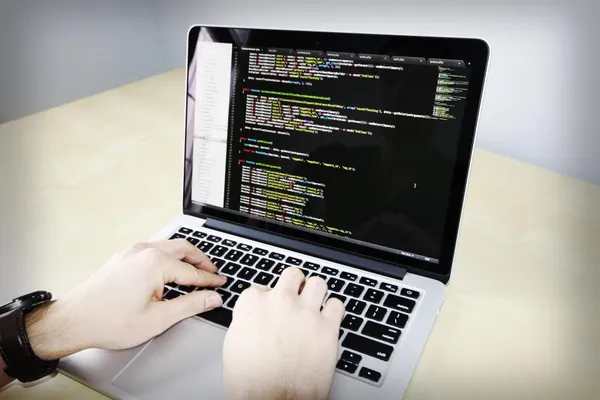 Hands typing code on a laptop