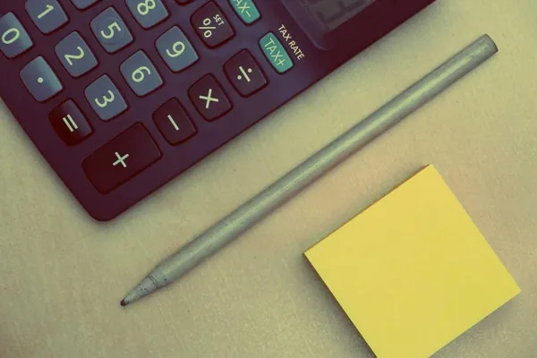 Calculator, pencil and sticky note on a desk