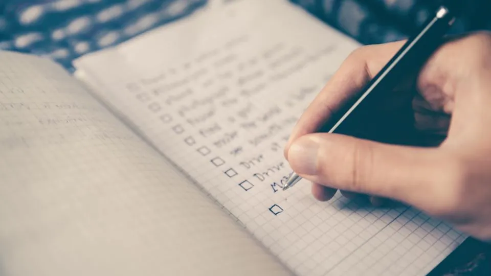 Hand ticking off a checklist in a notebook