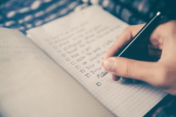 Hand ticking off a checklist in a notebook