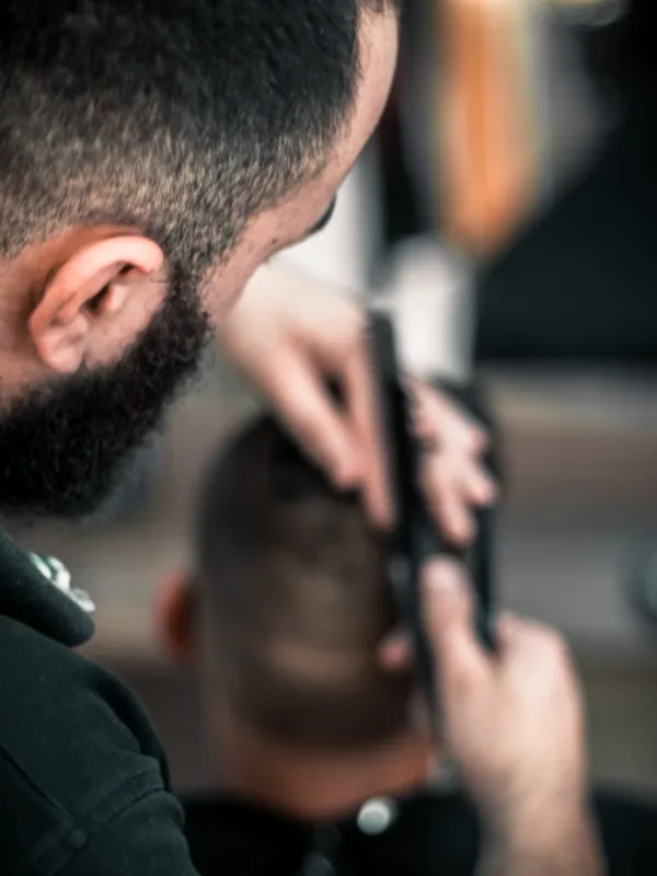 Barber giving a client a fade with clippers