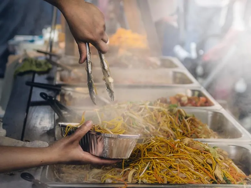 Caterer serving hot food from a buffet station