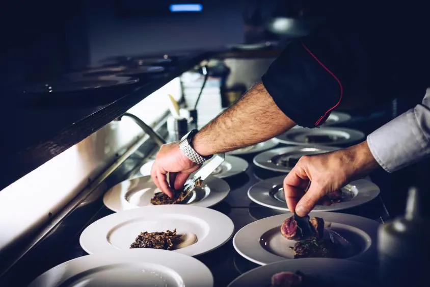 Chef plating desserts in a row in a professional kitchen