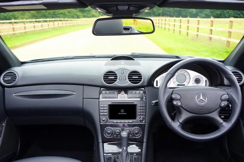 Inside a right-hand-drive car looking out at a country road