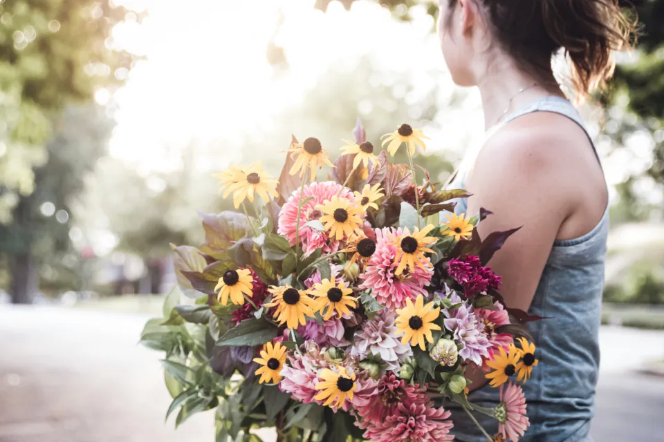 Florist carrying a large bouquet of sunflowers and pink blooms
