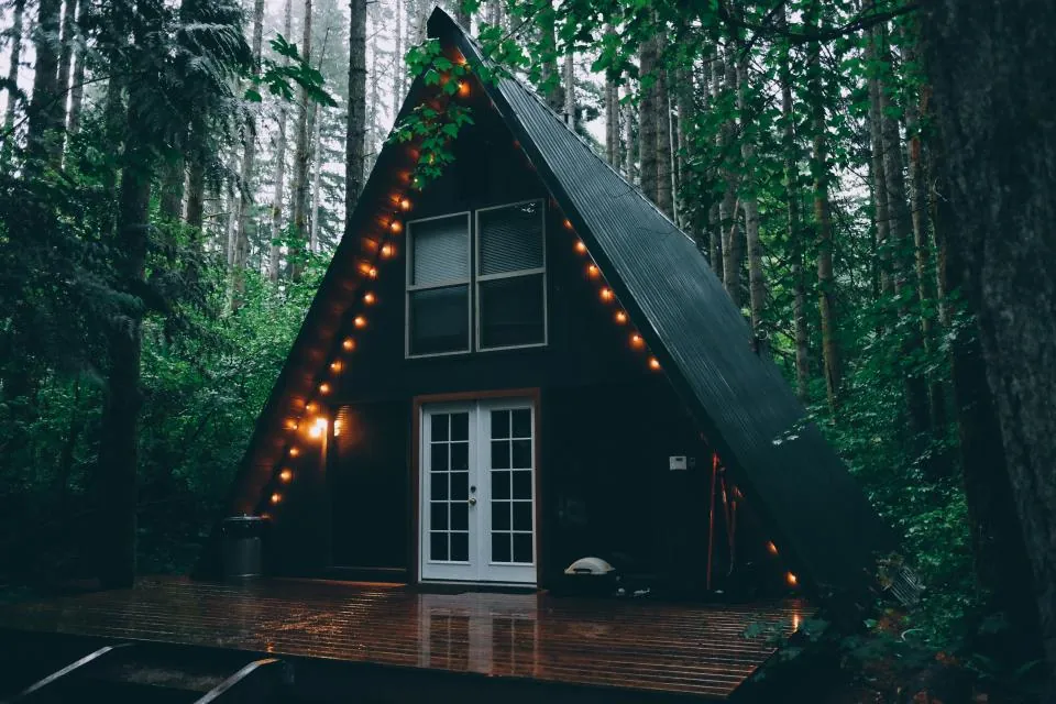 A-frame cabin with fairy lights in a forest