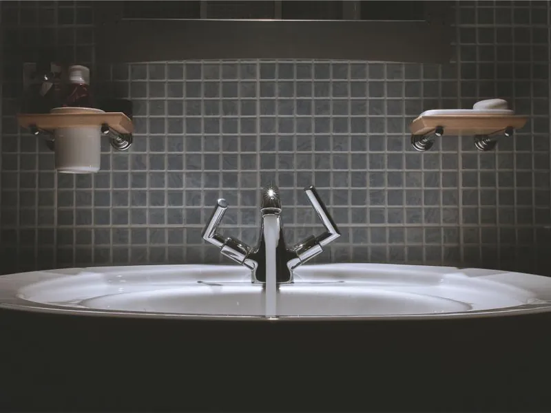Basin and mixer tap against dark tiles