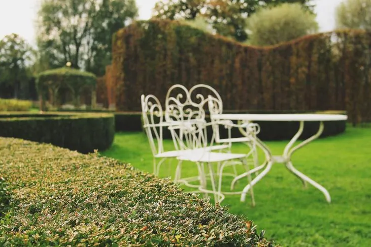Formal garden with clipped hedges, lawn and white garden furniture