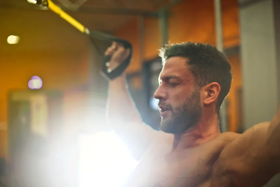 Personal trainer working out with suspension straps