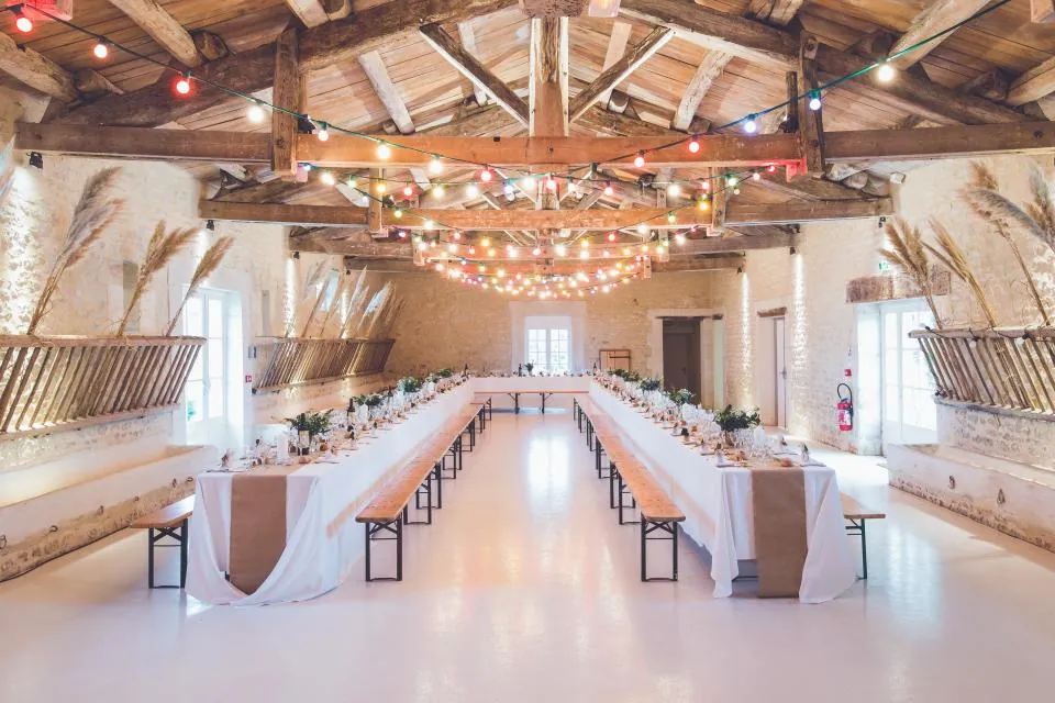 Barn wedding reception with long tables and festoon lights