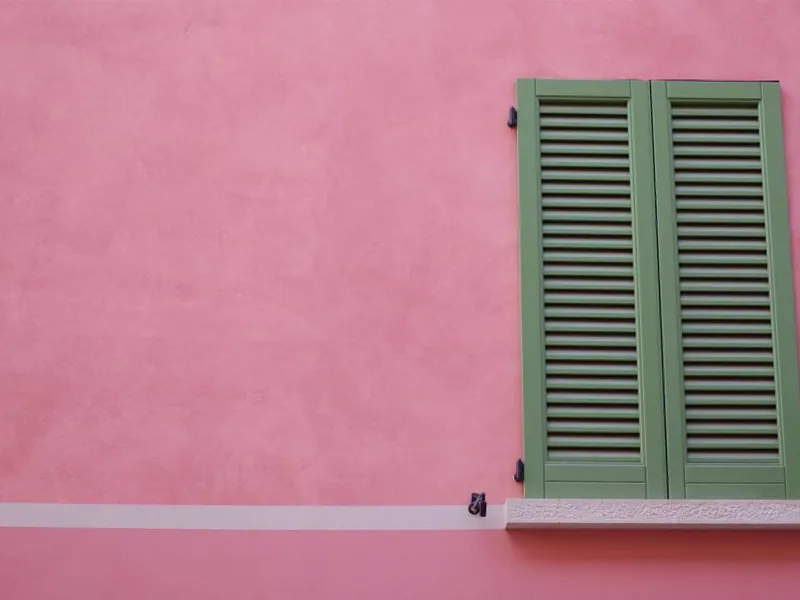 Green wooden shutters on a pink wall