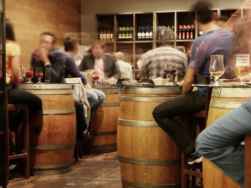 Guests at a wine tasting around barrel tables