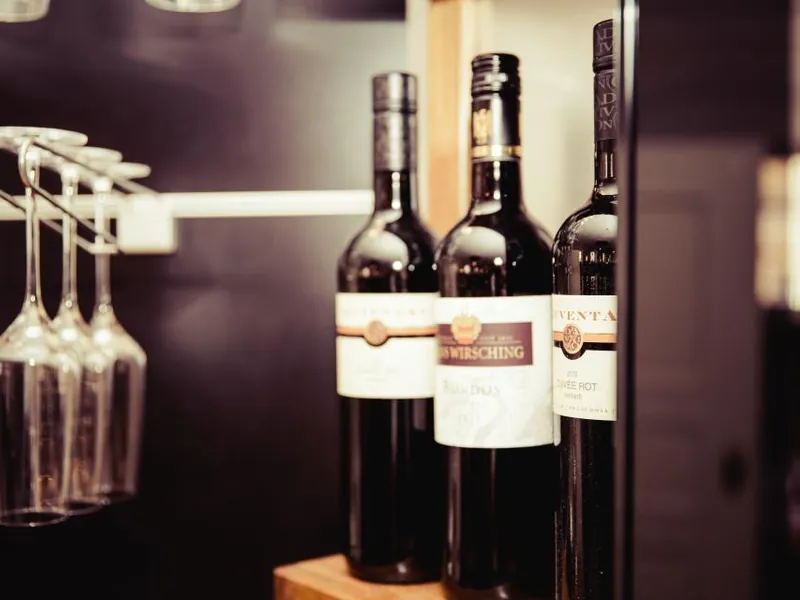 Bottles of red wine beside hanging wine glasses